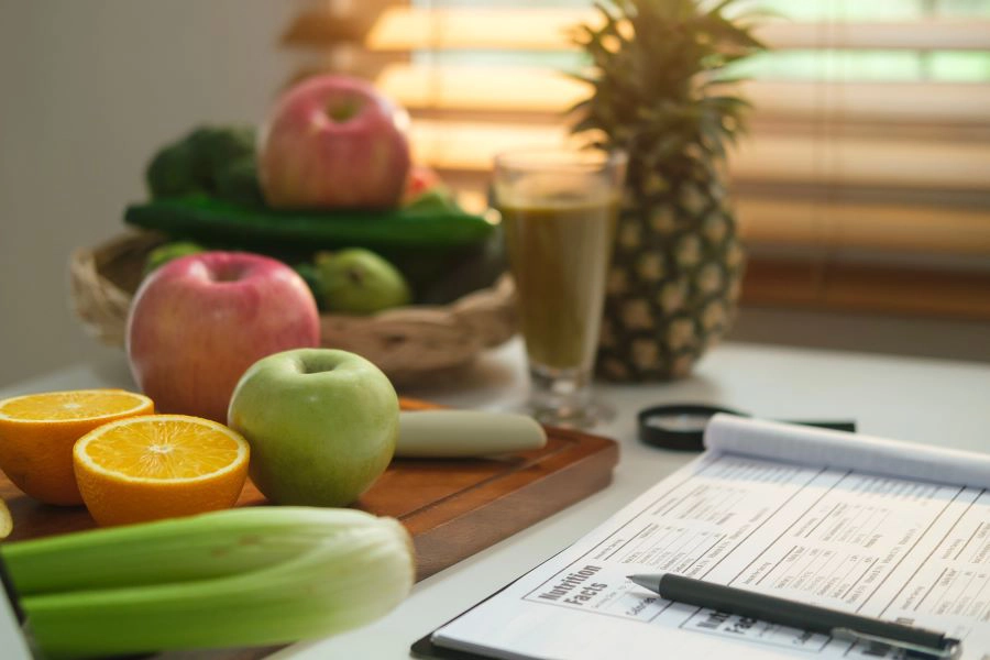 Diet plan on paper and fresh vegetables and fruits on white table